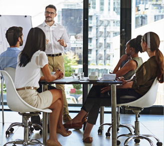 Man giving a whiteboard presentation to colleagues in a boardroom